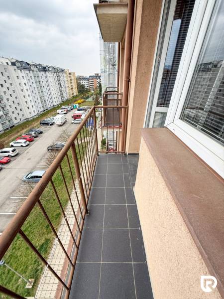Balkon garsonky na Východní ulici v Trenčíně s výhledem na parkoviště a budovy.