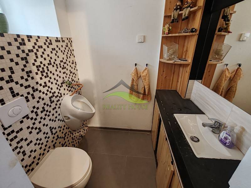 Koupelna v rodinném domě s umyvadlem, zrcadlem a mozaikovými obklady.