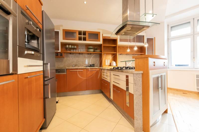 Kuchyně ve 4-pokojovém bytě s dřevěným dekorem a spotřebiči z nerezové oceli.