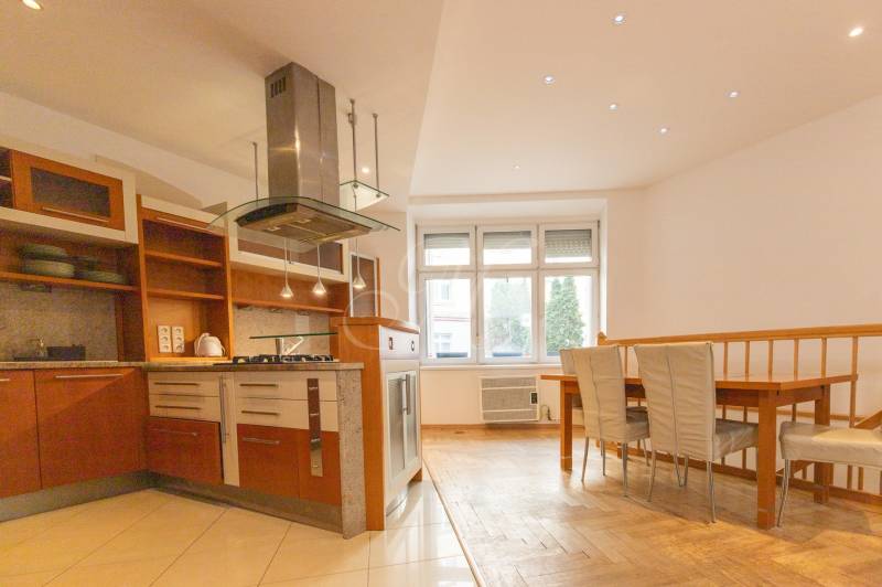 Kuchyně s jídelním koutem ve 4-pokojovém bytě, podlaha s dřevěným dekorem, bílá stěna.