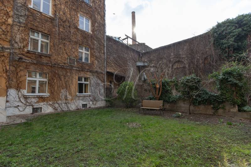 Dvůr obytného domu na Medenej ulici v Bratislavě - Staré Město s lavičkou a zelení.