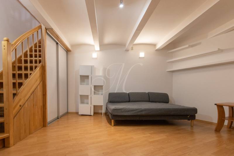 Obývací pokoj s pohovkou, schody a podlahou s dřevěným dekorem ve 4pokojovém bytě.