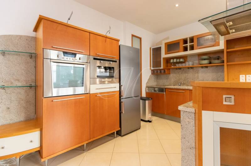 Kuchyně ve 4-pokojovém bytě s nerezovými spotřebiči a dřevěnými skříňkami.