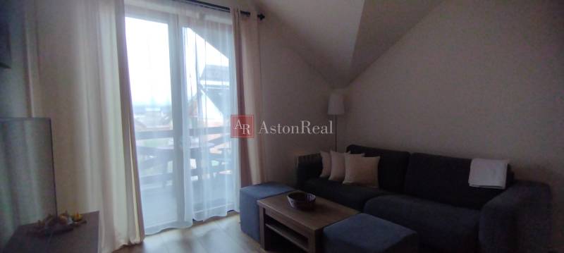 Obývací pokoj v 2pokojovém bytě s pohovkou, konferenčním stolkem a výhledem na balkon.