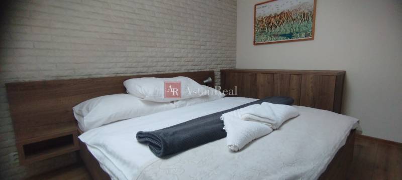 Ložnice s dřevěným nábytkem a obrazem, podlaha s dřevěným dekorem, dvoupokojový byt.