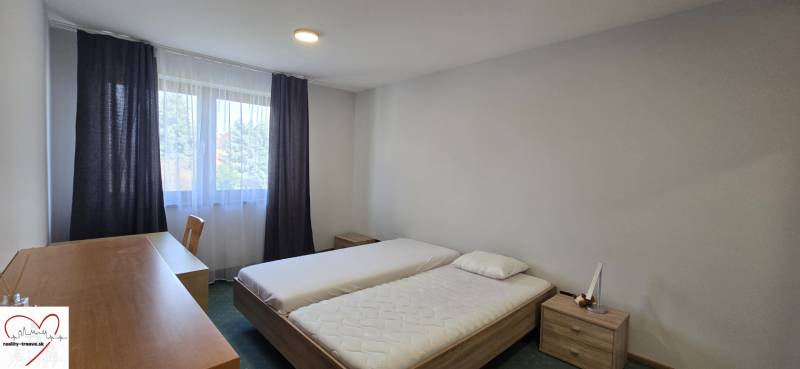 Ložnice s dvěma postelemi, psacím stolem a oknem ve 3-pokojovém bytě.
