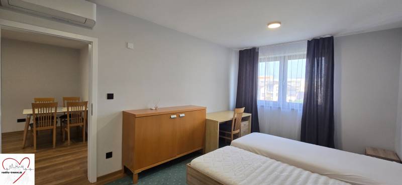 Ložnice s postelemi a nábytkem v třípokojovém bytě, bílé stěny, podlaha s dřevěným dekorem.