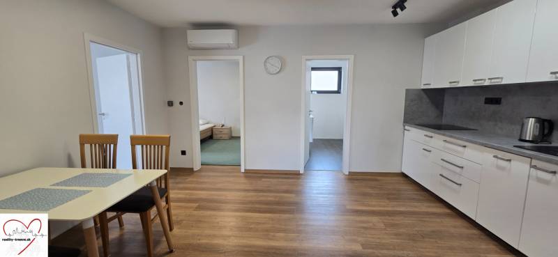 Kuchyně v 3pokojovém bytě s podlahou s dřevěným dekorem a jídelním stolem.