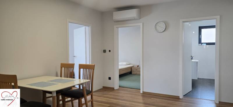 Jídelní stůl se židlemi a podlaha s dřevěným dekorem v 3-pokojovém bytě.