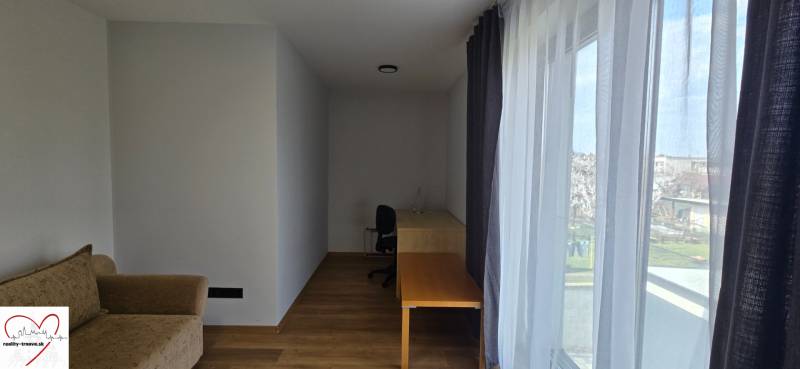 Pokoj v 3-pokojovém bytě s podlahou s dřevěným dekorem, stolem a pohovkou.