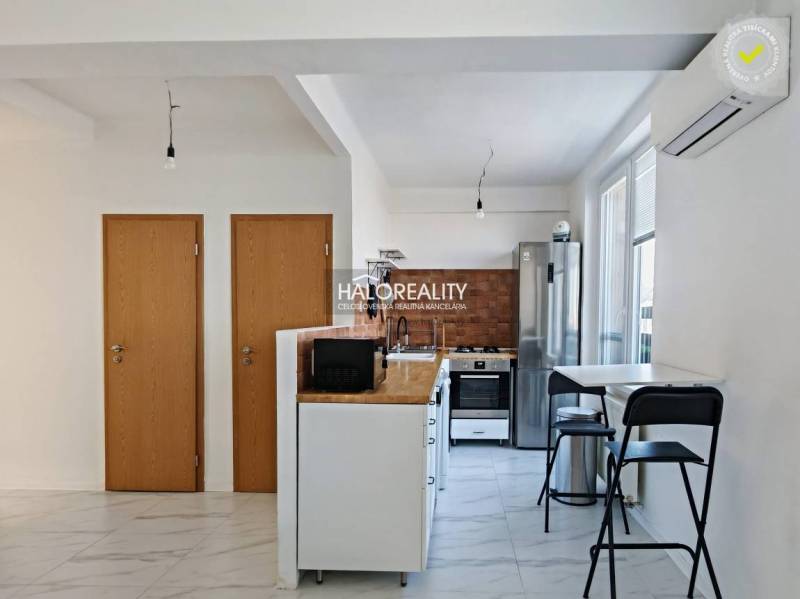 Kuchyně v 3-pokojovém bytě s bílými stěnami a spotřebiči, podlaha s bílým dekorem.