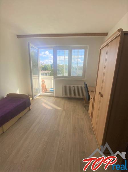 Světlý pokoj ve 4-pokojovém bytě s balkonem a podlahou s dřevěným dekorem.
