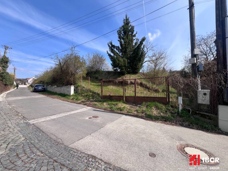 Pozemek na bydlení na Budovatelské ulici v Mariance s bránou a příjezdovou cestou.