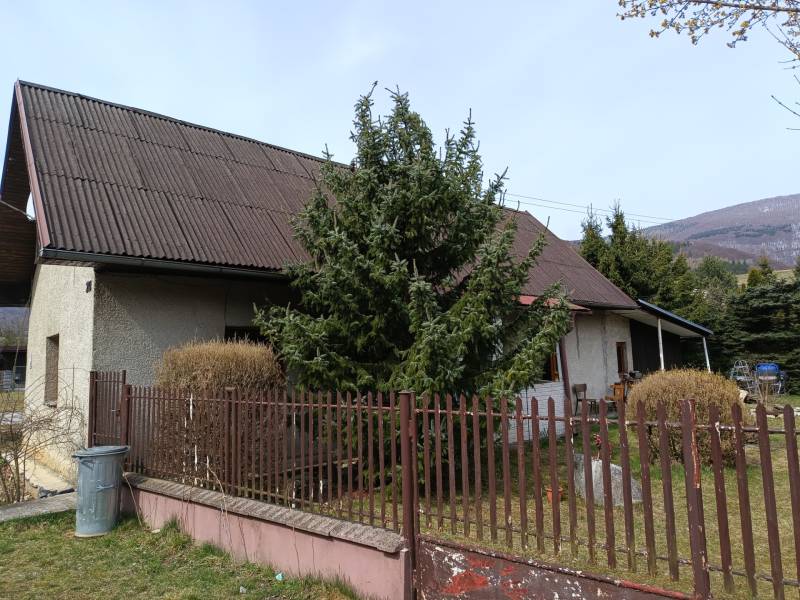 Rodinný dům ve Vrícku s oplocenou zahradou u jehličnatého stromu.