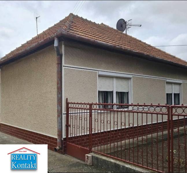 Rodinný dům v Radavě na Hlavní ulici s červenou střechou a bílými okenicemi.