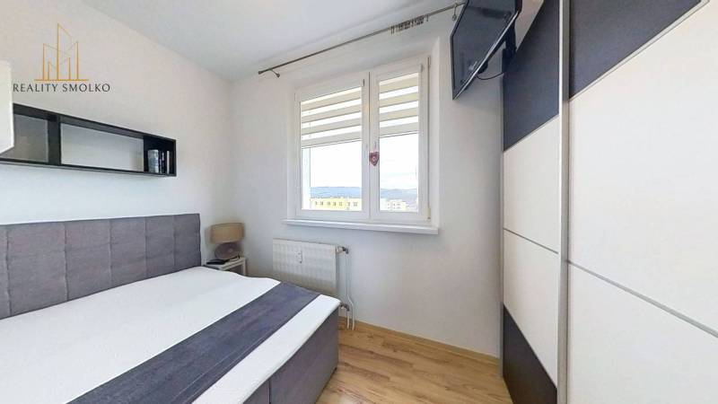 Ložnice s postelí a televizorem, podlaha s dřevěným dekorem v 3-pokojovém bytě.