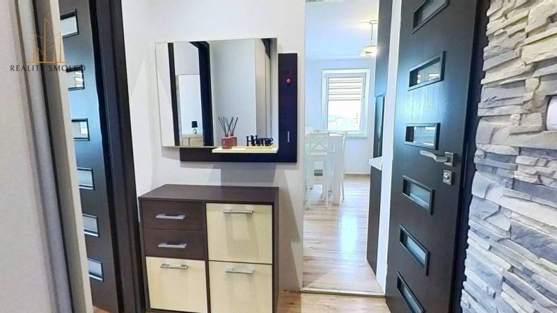 Chodba s dřevěným dekorem a obkladem ve 3-pokojovém bytě, skříňka se zrcadlem.