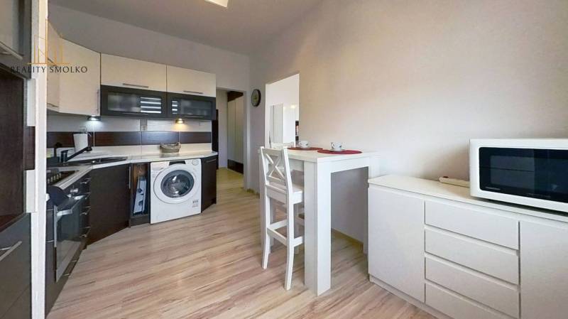 Kuchyně ve 3-pokojovém bytě s jídelním stolem a podlahou s dřevěným dekorem.