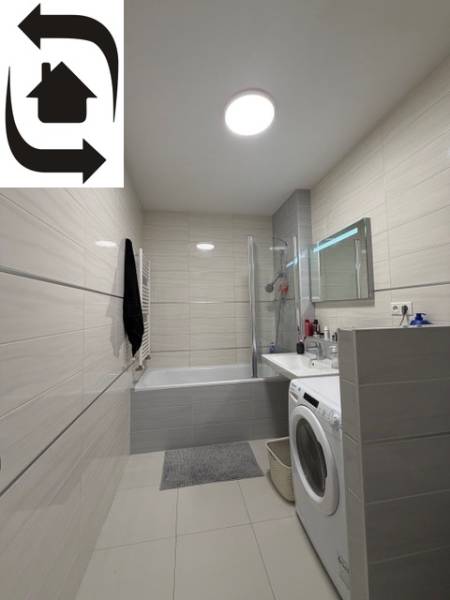 Koupelna v 2-pokojovém bytě se sprchovým koutem, vanou a pračkou.