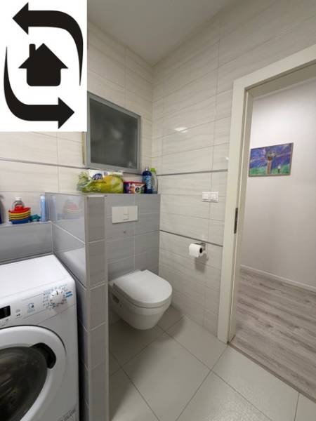 Koupelna s pračkou, toaletou a dlažbou v 2-pokojovém bytě.