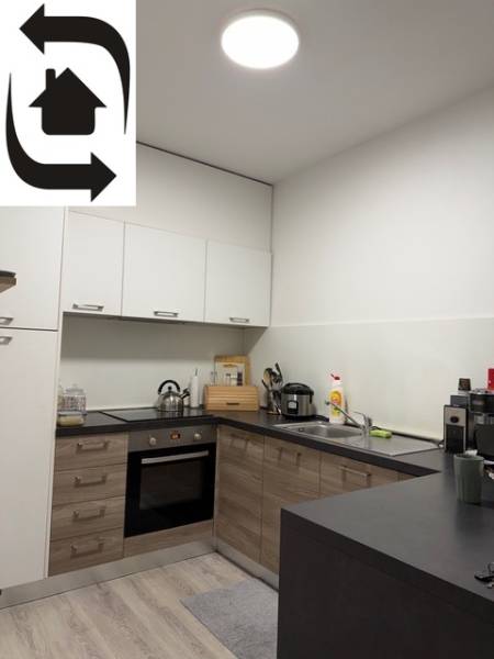 Kuchyně v 2-pokojovém bytě s podlahou s dřevěným dekorem a bílými skříňkami.