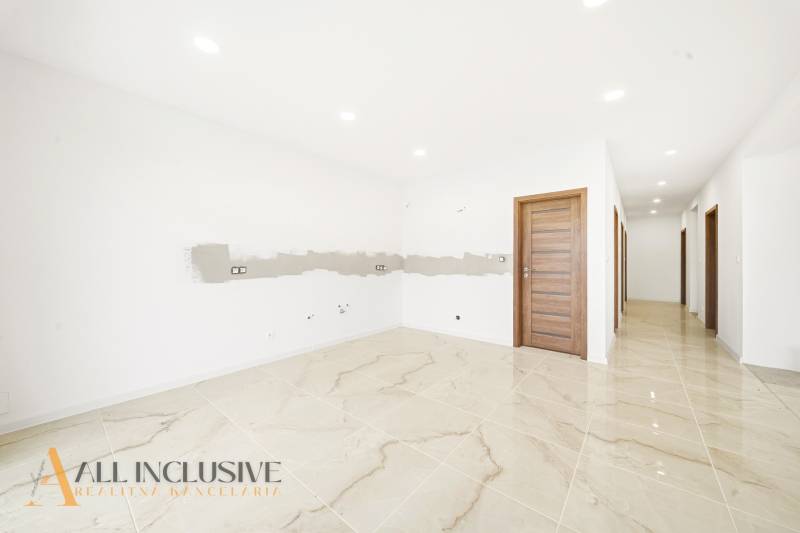 Interiér rodinného domu s lesklou dlažbou a dřevěnými dveřmi.