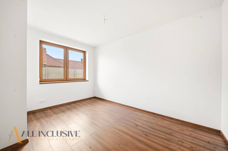 Bílá stěna a podlaha s dřevěným dekorem v místnosti rodinného domu.