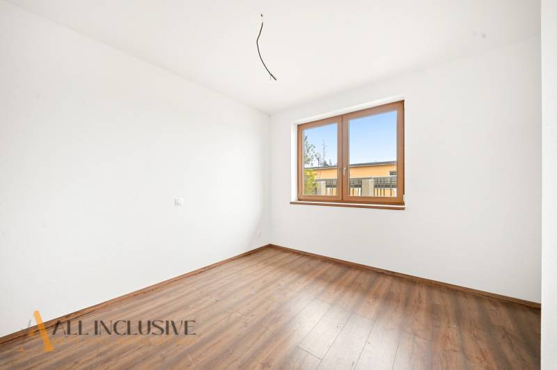 Pokoj v rodinném domě s podlahou s dřevěným dekorem a velkým oknem.