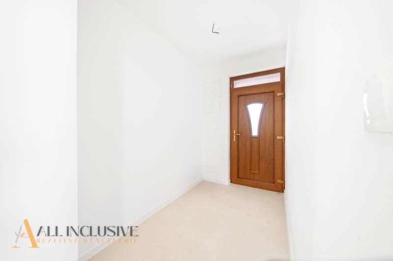 Vstupní chodba rodinného domu s bílými stěnami a tmavými dveřmi.