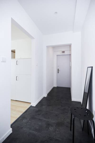 Chodba s tmavou podlahou a bílými stěnami v 2-pokojovém bytě.