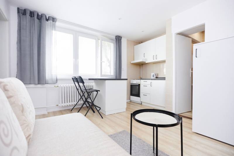 Kuchyně v 2-pokojovém bytě s bílým nábytkem a podlahou s dřevěným dekorem.