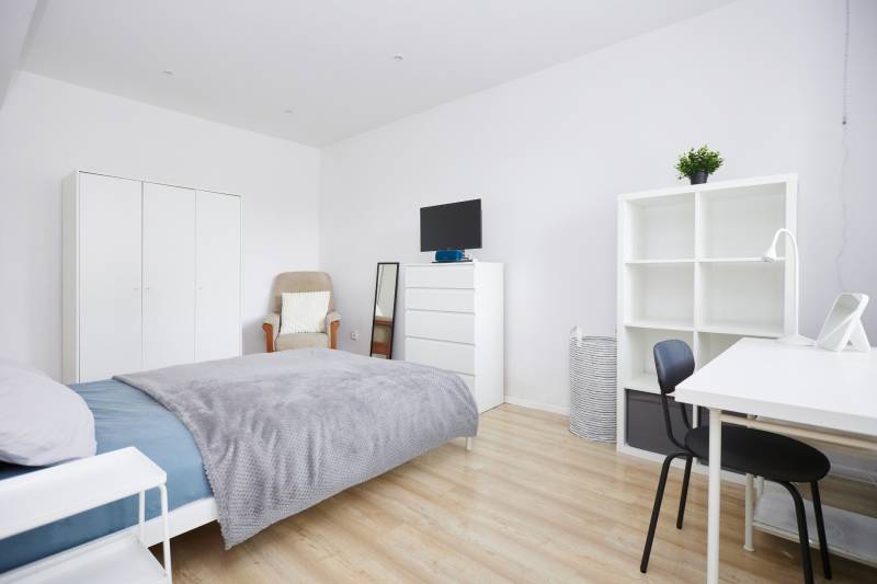 Ložnice v 2-pokojovém bytě s bílým nábytkem a podlahou s dřevěným dekorem.