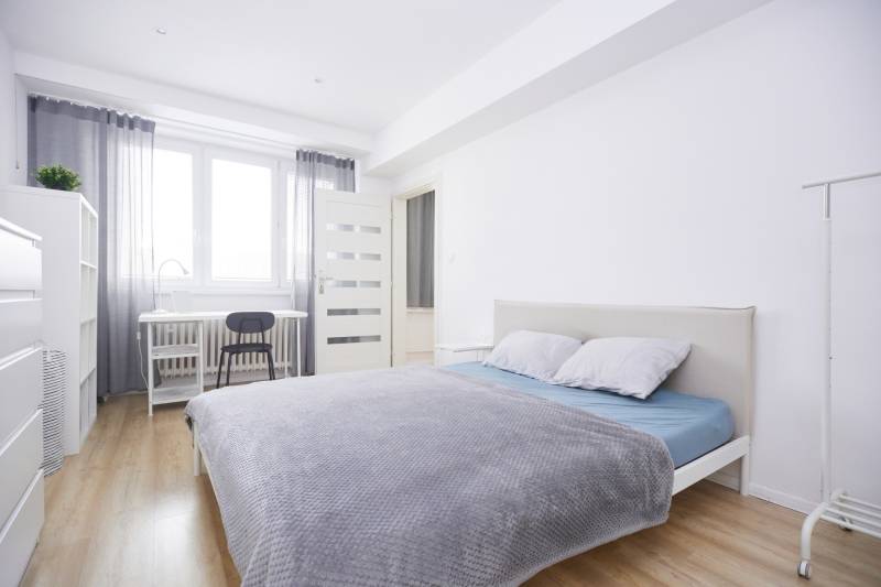 Světlá ložnice v 2-pokojovém bytě s psacím stolem a podlahou s dřevěným dekorem.