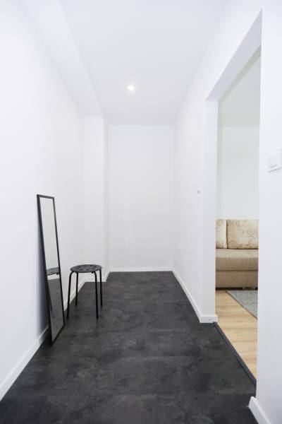 Úzká chodba v 2-pokojovém bytě s černou podlahou a zrcadlem.