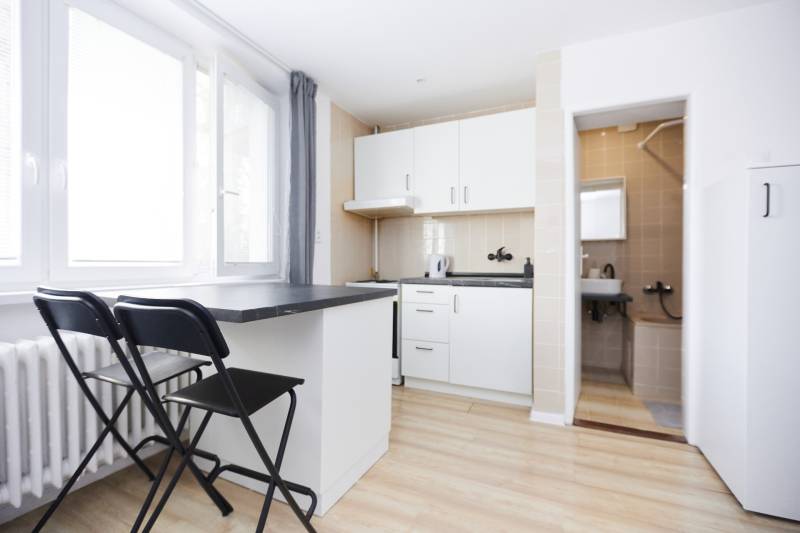 Kuchyně v 2-pokojovém bytě s barovým pultem a podlahou s dřevěným dekorem.