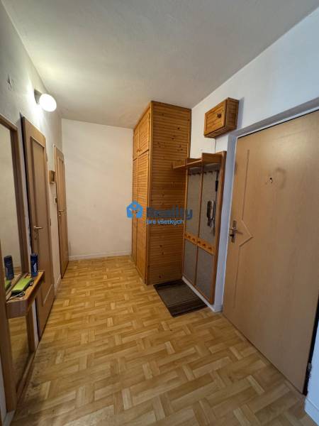 Chodba s podlahou s dřevěným dekorem a vestavěnými skříněmi v 2-pokojovém bytě.