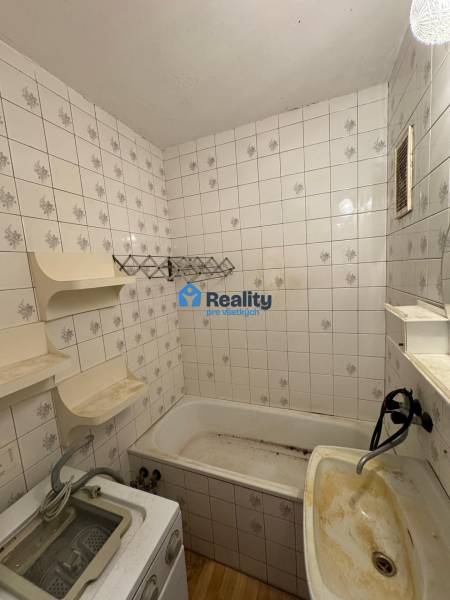 Koupelna v 2-pokojovém bytě s vanou, umyvadlem a dlaždičkami.