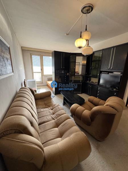 Obývací pokoj v 2-pokojovém bytě s pohodlnou pohovkou a skříňovou sestavou.