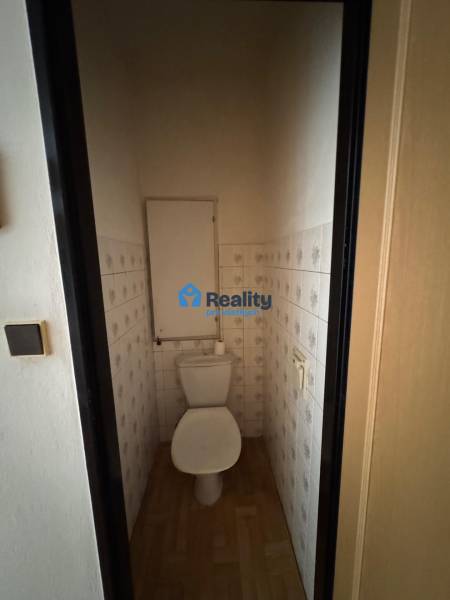 Toaleta s dlažbou a podlahou s dřevěným dekorem v 2-pokojovém bytě.