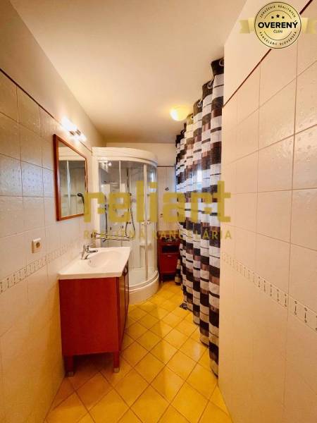 Koupelna v rodinném domě s umyvadlem, sprchovým koutem a dlažbou.