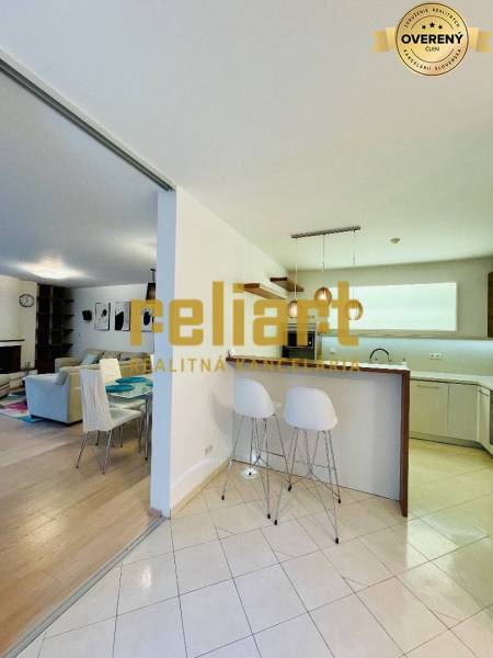 Kuchyně a obývací pokoj v rodinném domě s barovým pultem a židlemi.