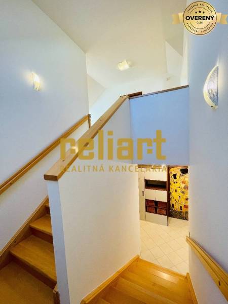 Interiér rodinného domu se schodištěm a podlahou s dřevěným dekorem.