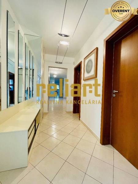 Chodba v rodinném domě s dlažbou, zrcadlovou stěnou a dřevěnými dveřmi.