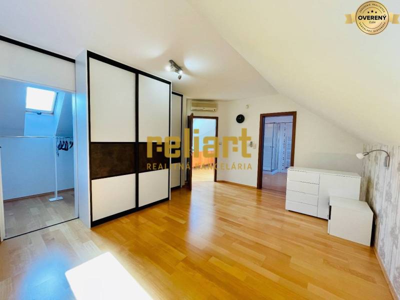 Podkrovní pokoj s podlahou s dřevěným dekorem a vestavěnou skříní v rodinném domě.