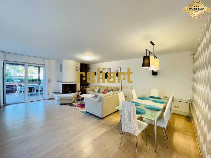 Interiér rodinného domu s krbem, podlahou s dřevěným dekorem a jídelním stolem.