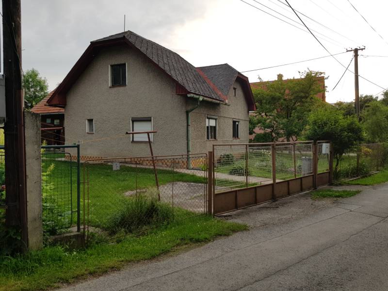 Rodinný dům na ulici Blatnica ve městě Blatnica s jednoduchou zahradou a kovovým plotem.