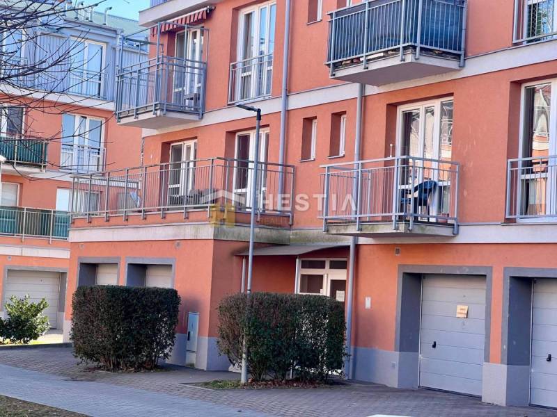 Obrázek zachycuje exteriér bytového domu s balkony a garážemi v 1-pokojovém bytě.