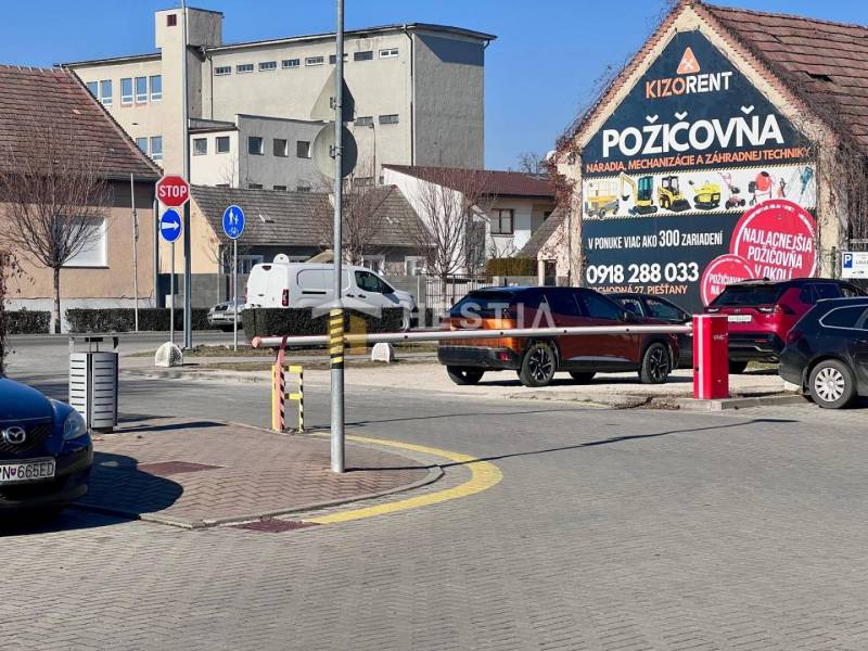 Ulice ve městě s auty, cyklostezkou a budovou Půjčovny nářadí, 1-pokojový byt nezmíněn.