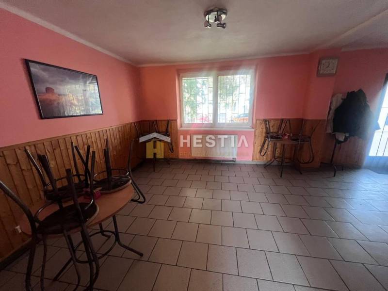 Gastro prostory s dlažbou, růžovými stěnami a stohovaným nábytkem.