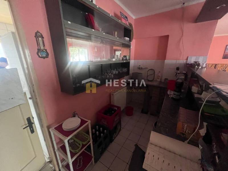 Kuchyňský kout v gastro prostorech s pultem, policemi a vybavením.